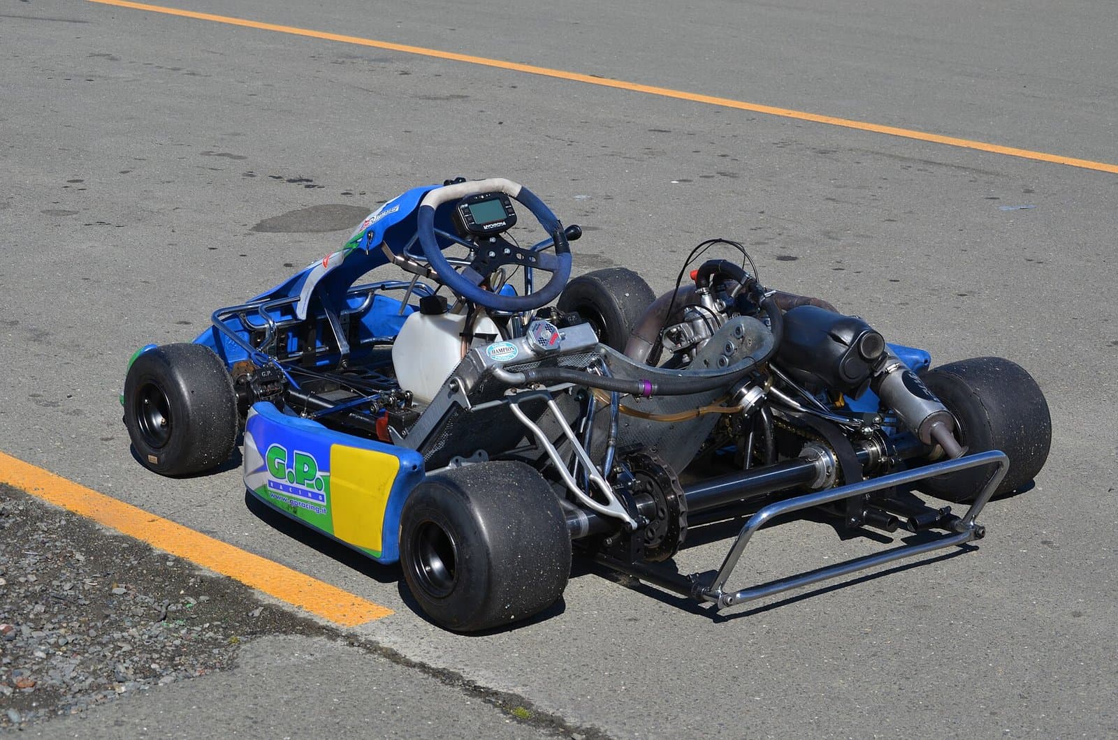A racing kart parked on asphalt with a MyChron4 lap timer mounted on the steering wheel