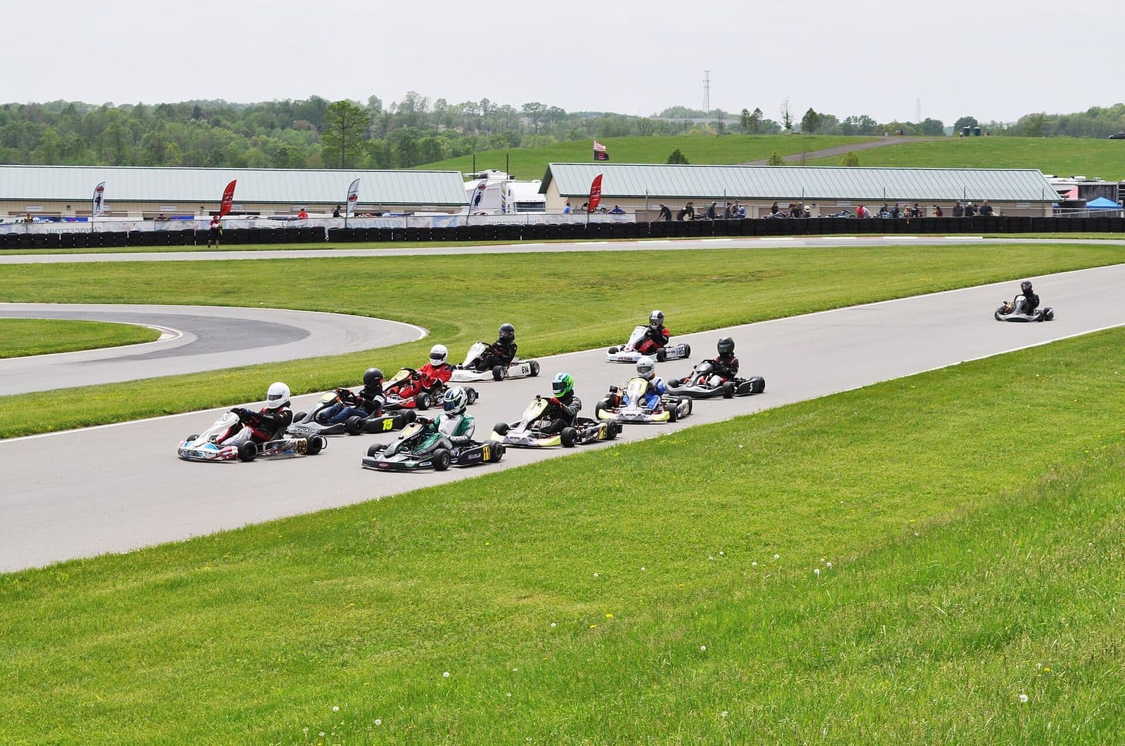 A pack of karts racing out of a bend at a club circuit