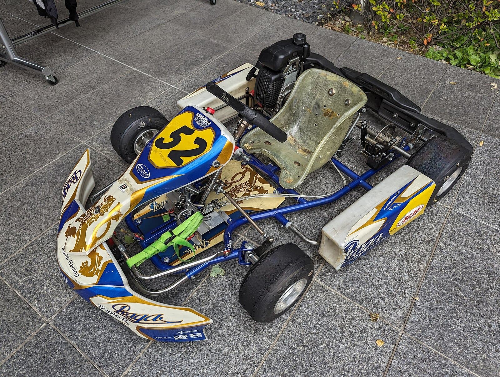 A bare fibreglass kart seat bolted into a blue kart chassis frame, seen from the front and above
