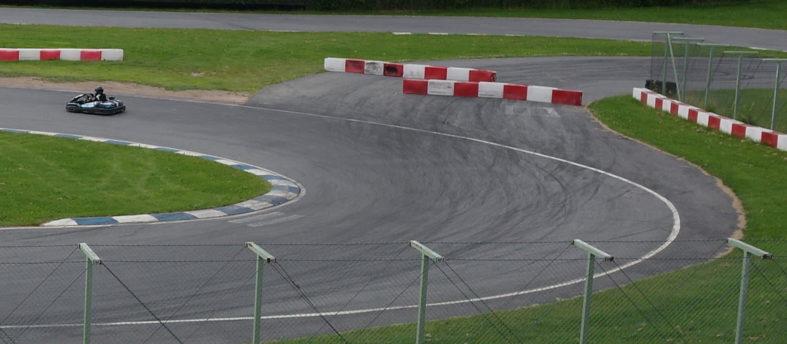 A kart on a circuit in Finland, with dark rubber marks scuffed across the surface through a corner