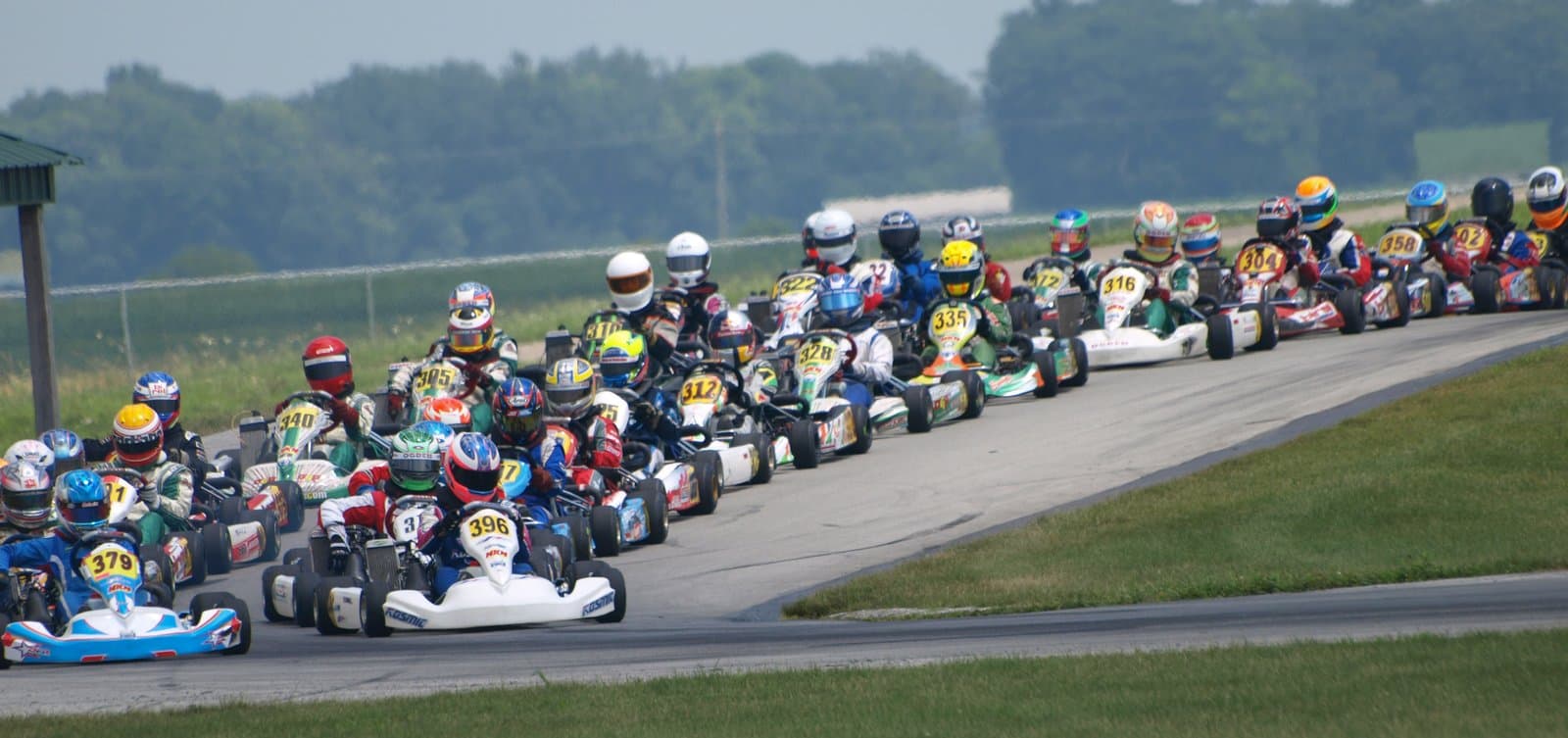 A tightly packed pack of karts following each other round a corner on a parade lap