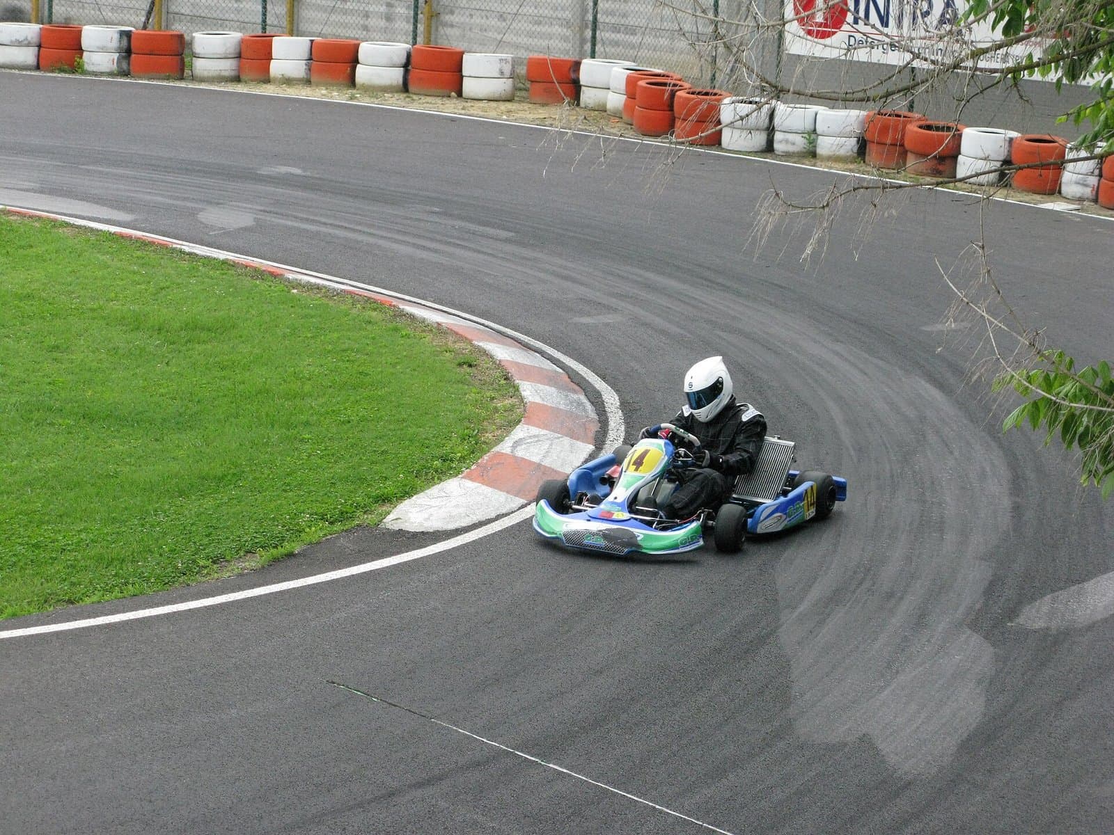 A kart takes a corner with dark arcs of tire marks across the track surface